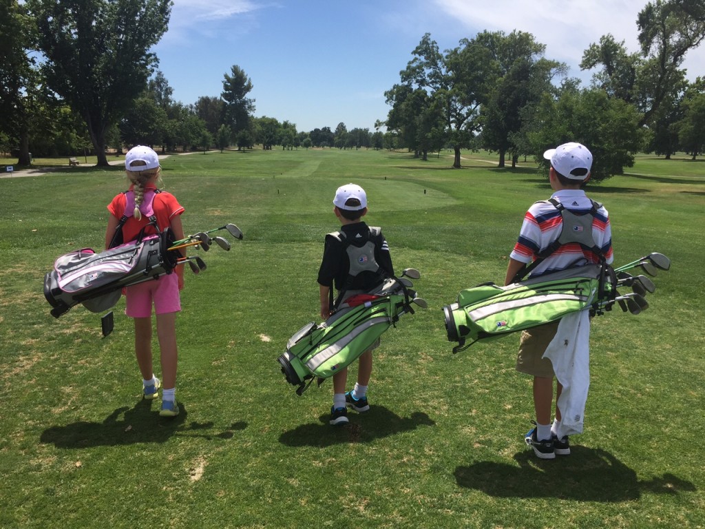 Three Junior Golfers with carry bags on Golf Course