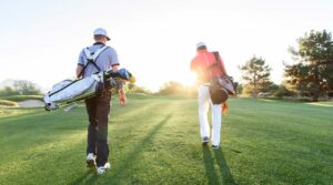 Two Teen Boys Walking on Golf Course carrying golf bags