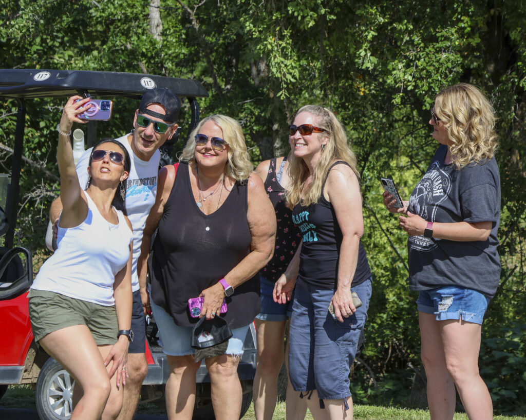 A group of 4 female fans taking a picture with Craig Campbell. One of them is holding the camera to take it as a selfie.