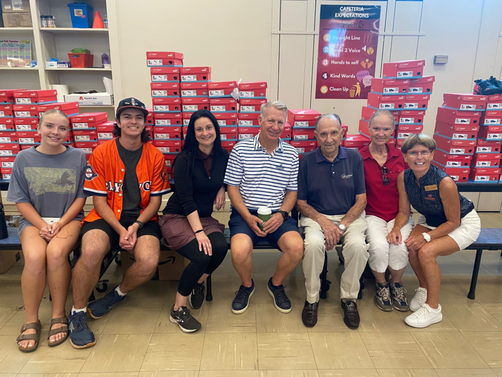 Volunteers for Morton Golf Foundation pose in front of stacks of Puma shoe boxes