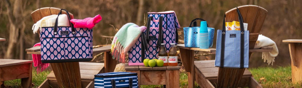 Several SCOUT bags are sitting on outdoor furniture. There are three purple and blue patterned bags and 3 blue and white patterned bags. This is from their fall collection.