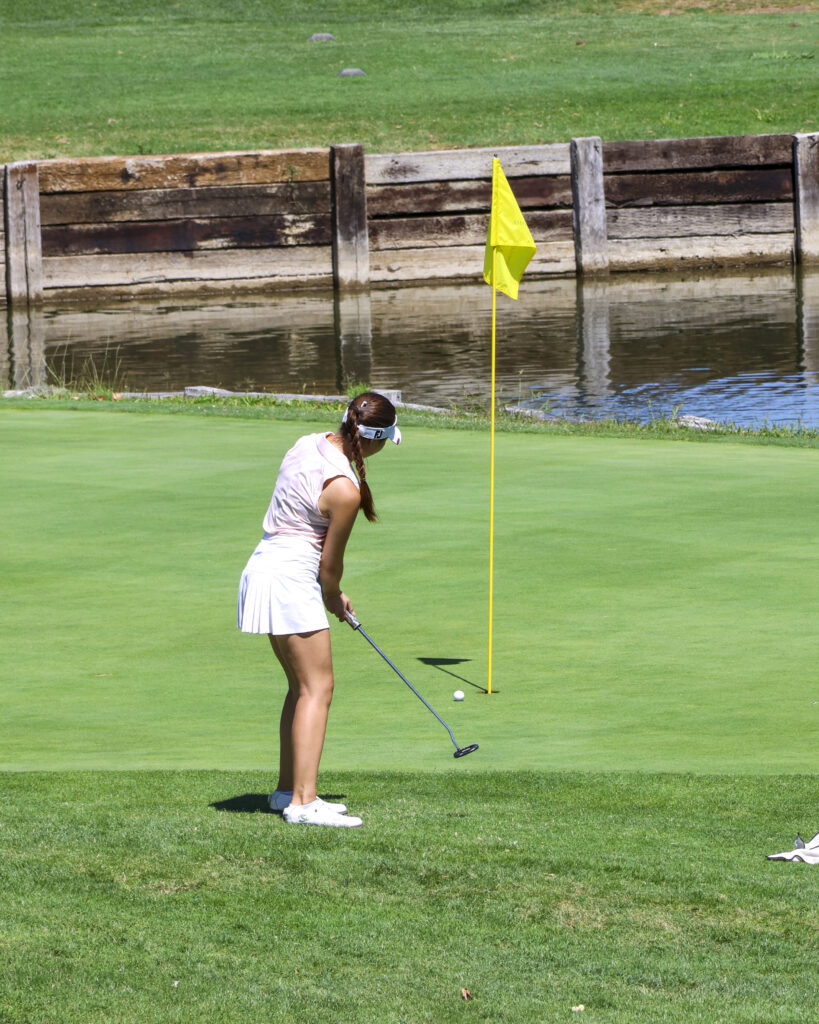 Sienna Lyford is putting on #13, watching her ball as it rolls towards the hole.