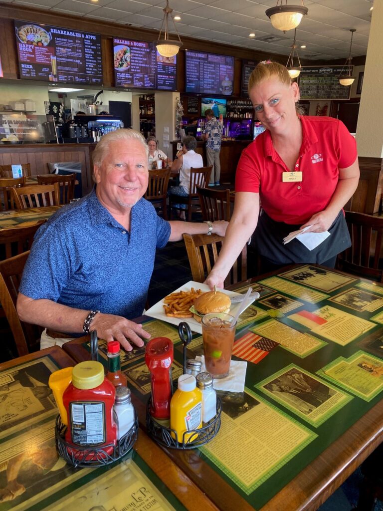 Server bringing hamburger and French fries to customer at MacKenzie's Sports Bar and Grille