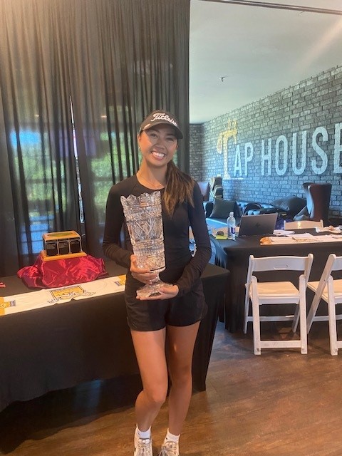 Erica Villegas smiling while holding the Womens Amateur State Fair Trophy in the Bartley Cavanaugh Tap House.