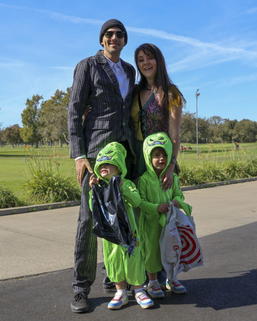 A family of 4 poses for a photo, all dressed like Nightmare Before Christmas Characters. The father is Jack Skellington, the mother is Sally, and the two boys are Oogie Boogie.