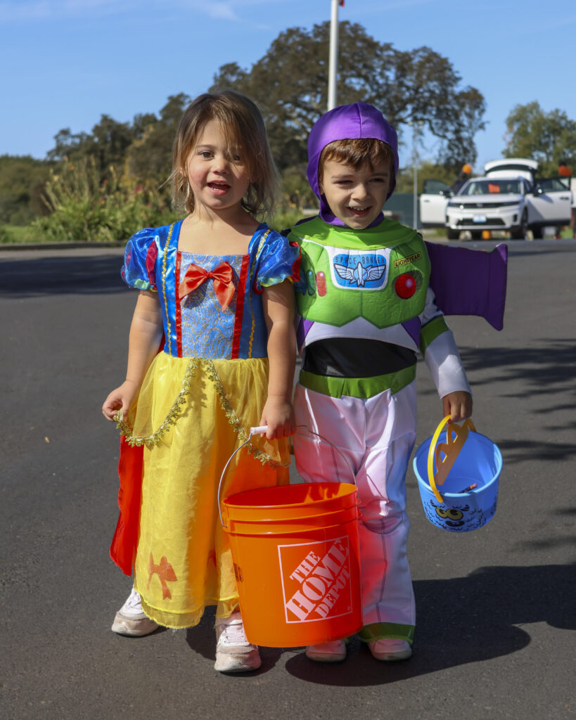 Two kids are posing for a photo. One is dressed like Snow White and the other is dressed like Buzz Lightyear.