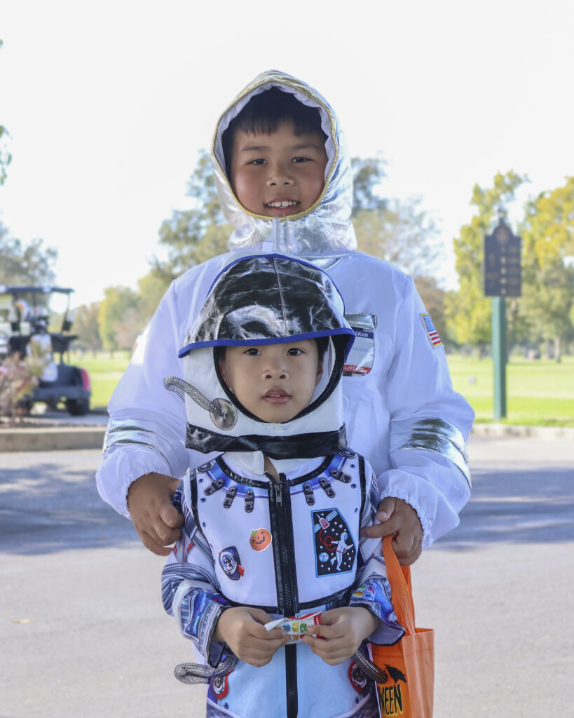 Two brothers pose for a photo, both in astronaut costumes.