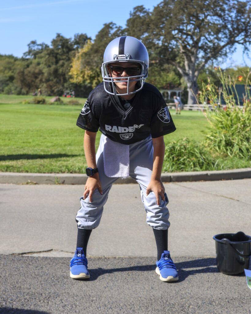 A child poses like a quarterback in a Raiders football outfit.