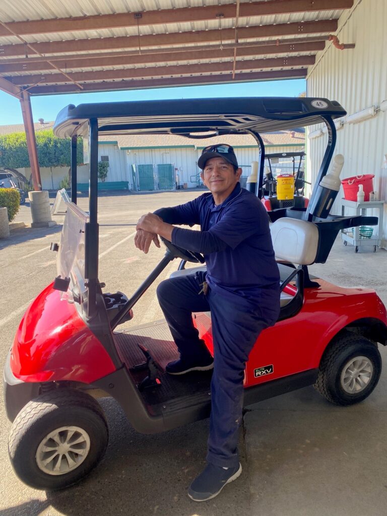 Man sitting in golf cart in front of cart barn